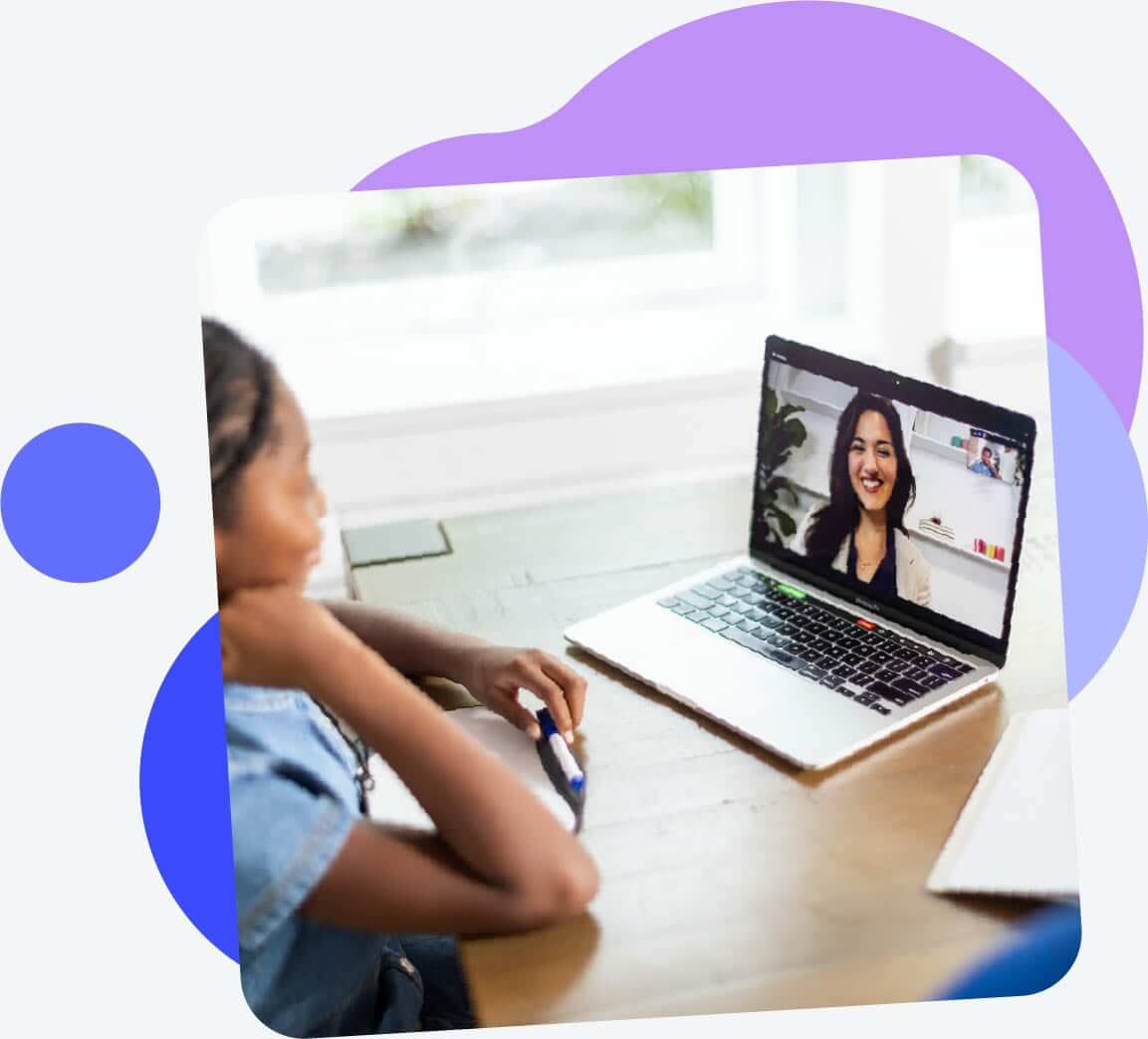 girl looking and smiling at the screen of a laptop with a Lexercise therapist on the screen